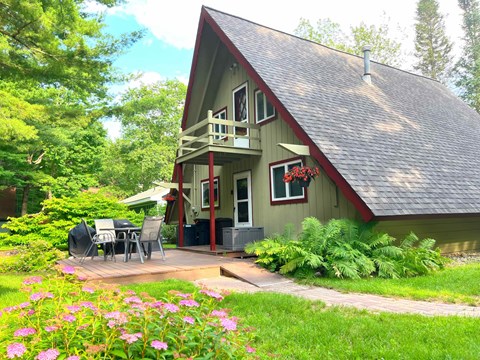 A green house with a red roof and a balcony.