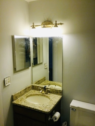 A bathroom with a sink, mirror, and toilet paper.