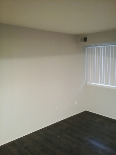 A room with a window and a wooden floor.