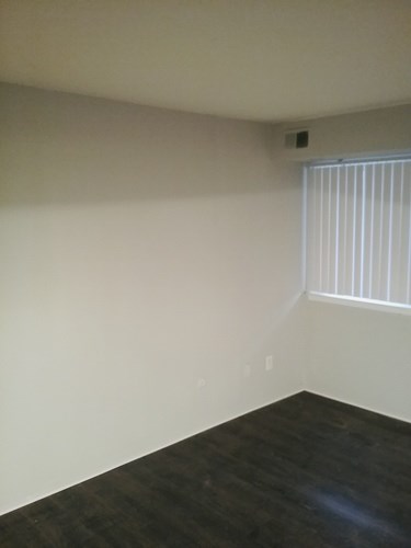 A room with a window and a wooden floor.