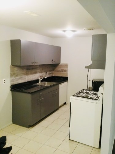 A kitchen with a white dishwasher and black countertops.