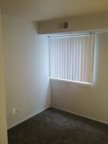A room with a window covered by white blinds.