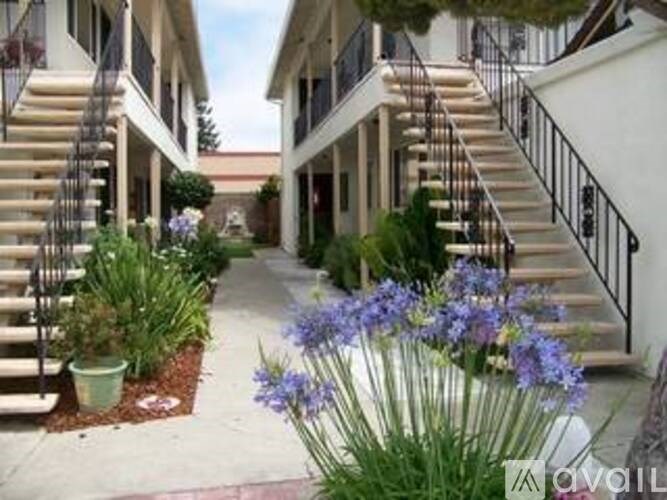 A white building with a staircase and a flower bed in front.