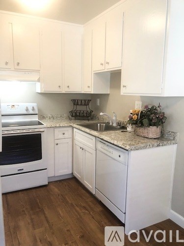A kitchen with white cabinets and a white stove top oven.