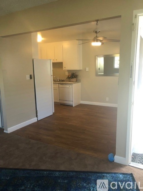A kitchen with white appliances and wooden floors.