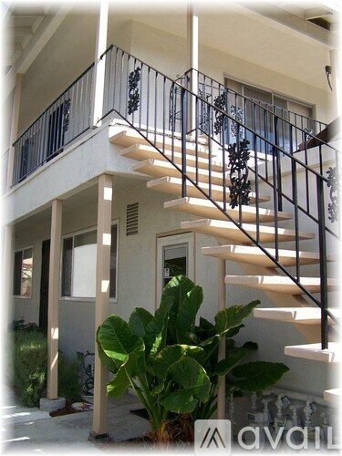 A white house with a black metal railing on the balcony.