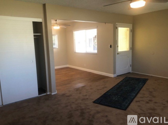 A room with a rug on the floor and a door on the left.