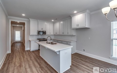 A kitchen with white cabinets and a wooden floor.