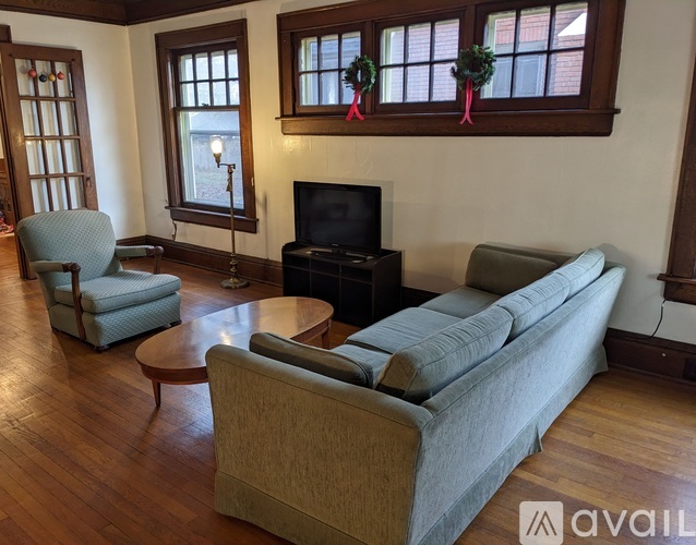 A living room with a grey couch, a green chair, and a wooden floor.