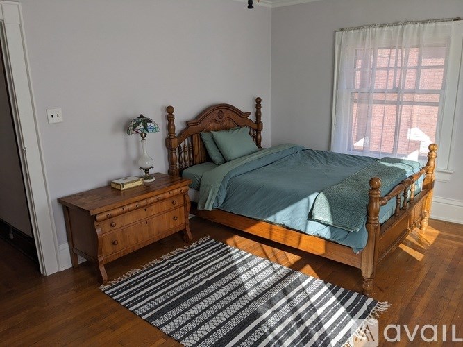 A bedroom with a bed, nightstand, and window.
