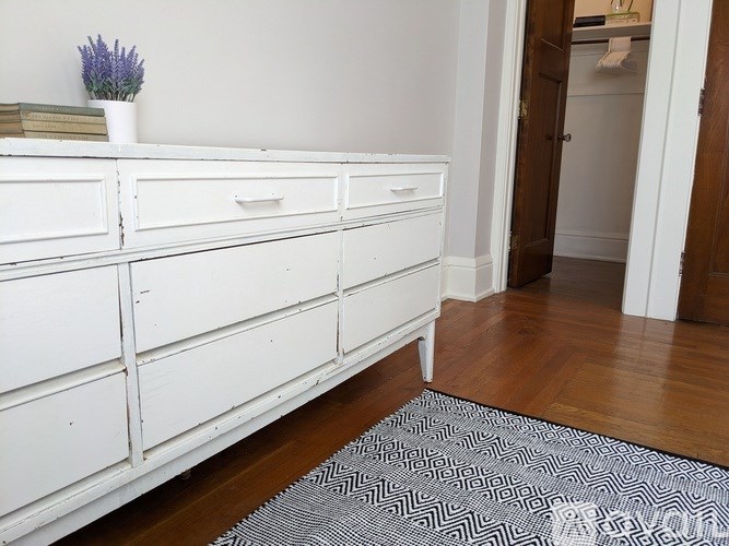 A white dresser with a vase of flowers on top.
