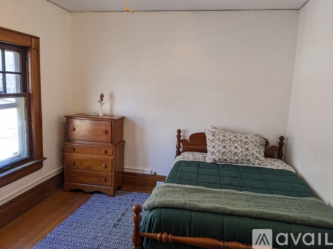 A bedroom with a bed, dresser, and window.