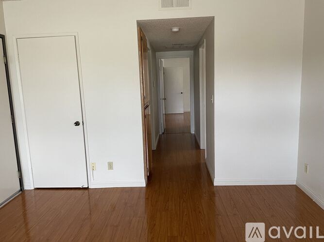 A hallway with a white door on the left and a white door on the right.