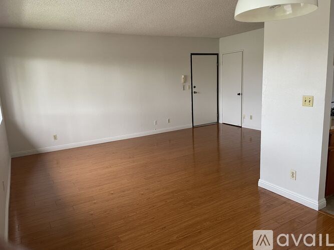 A room with wooden floors and white walls, with two doors and a light fixture.