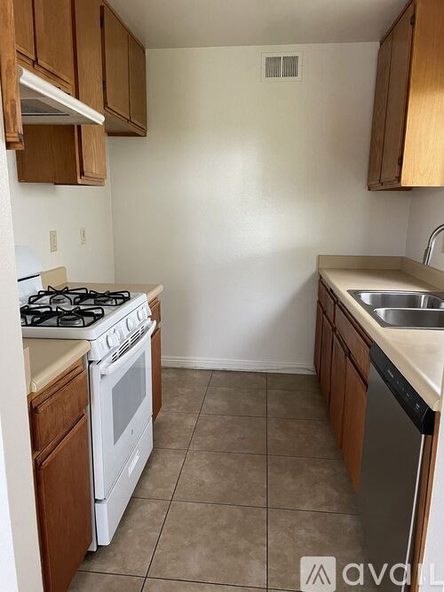A kitchen with a white stove top oven and a white dishwasher.