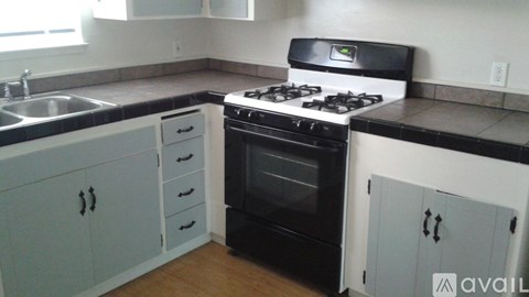 A kitchen with black and white cabinets and a black stove top oven.