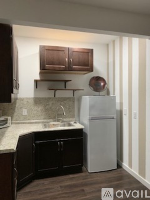 A kitchen with a white fridge and black cabinets.