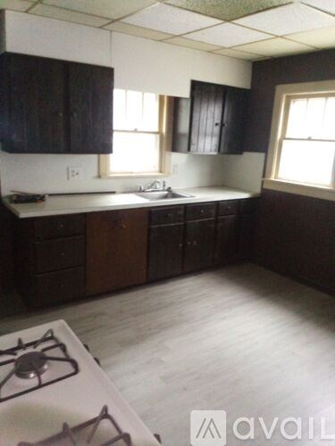 A kitchen with a white stove top and dark wood cabinets.