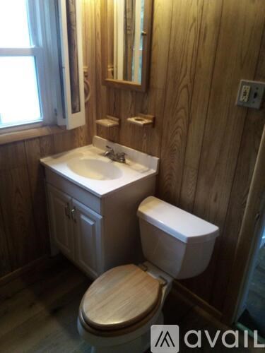 A wooden bathroom with a white sink and toilet.