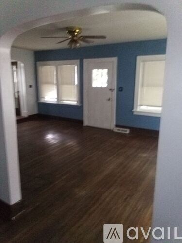 A room with a ceiling fan and wood flooring.