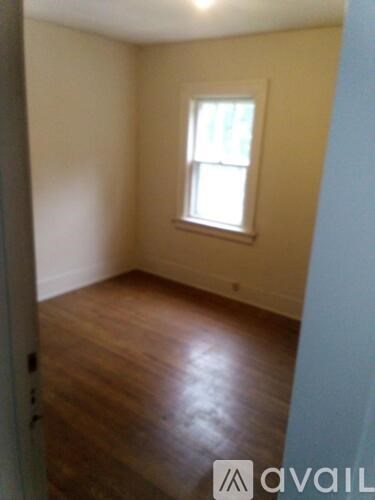 A room with a window and wooden floors.