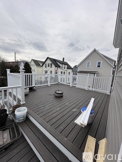 A deck with a white railing and a round table in the middle.