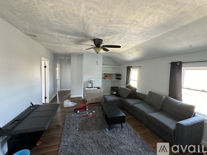 A living room with a grey couch and a black pool table.