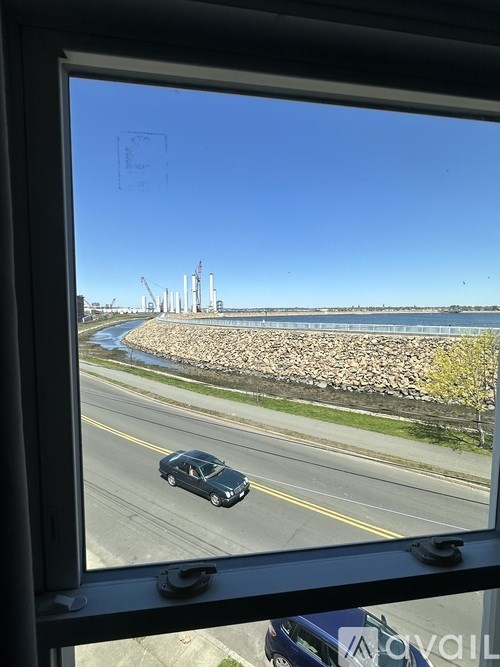 A car is driving on a road next to a body of water.