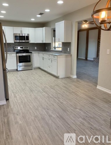 A kitchen with white cabinets and a wooden floor.