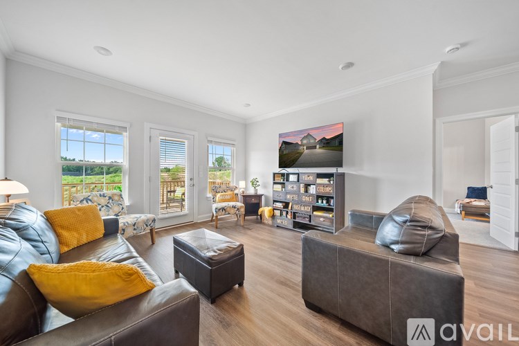 A living room with a brown leather couch and a flat screen TV mounted on the wall.