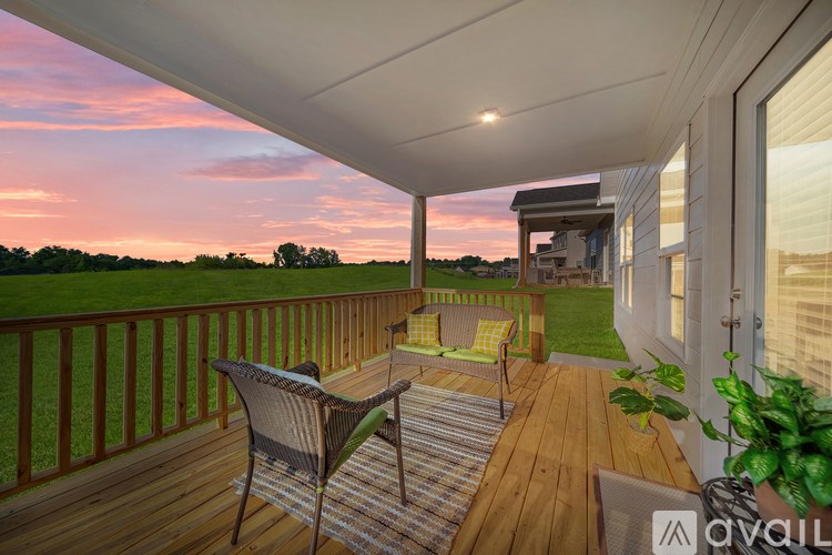 A balcony with a table and chairs overlooking a field.