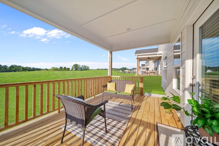 A patio with a table and chairs overlooking a grassy field.
