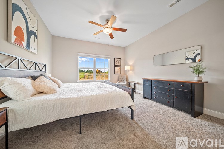 A bedroom with a bed, dresser, and a ceiling fan.