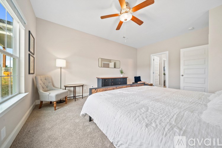 A bedroom with a large bed and a ceiling fan.