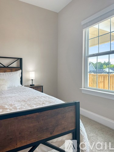 A bedroom with a bed, nightstand, and window.