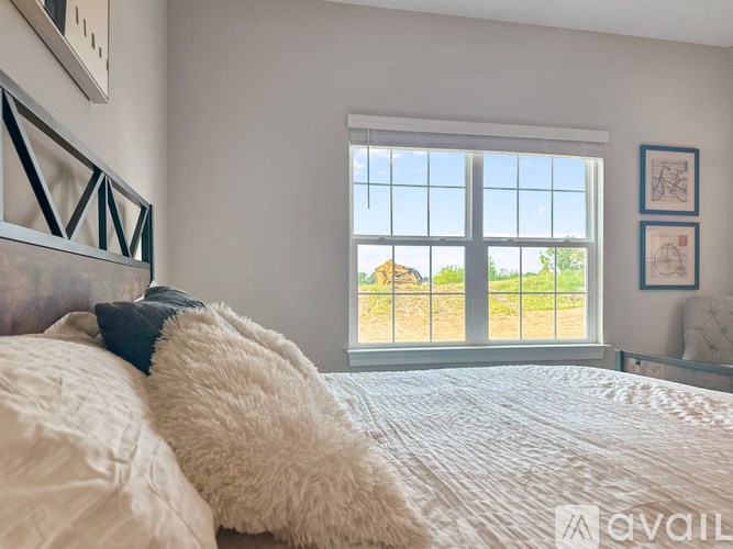 A bedroom with a large bed and a window overlooking a green landscape.