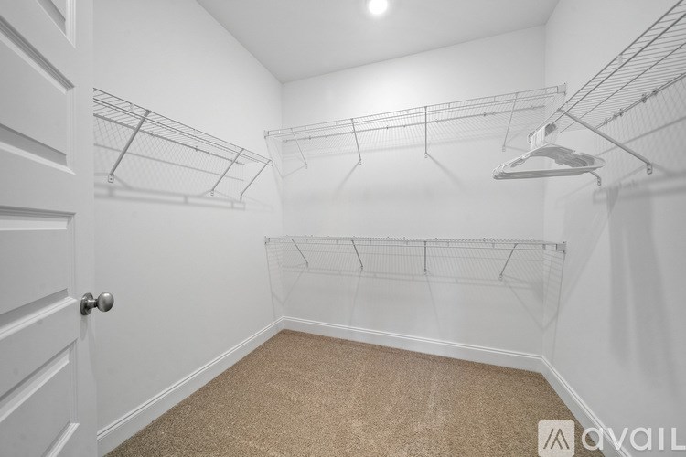 A white laundry room with a carpeted floor and a white door.