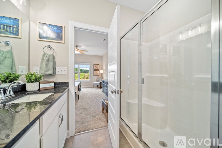 A bathroom with a glass shower door and a view of the backyard through the window.