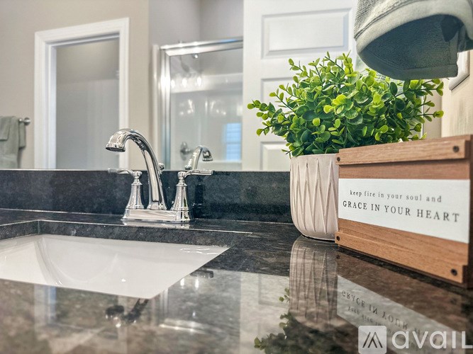 A bathroom sink with a plant and a wooden box with a quote on it.