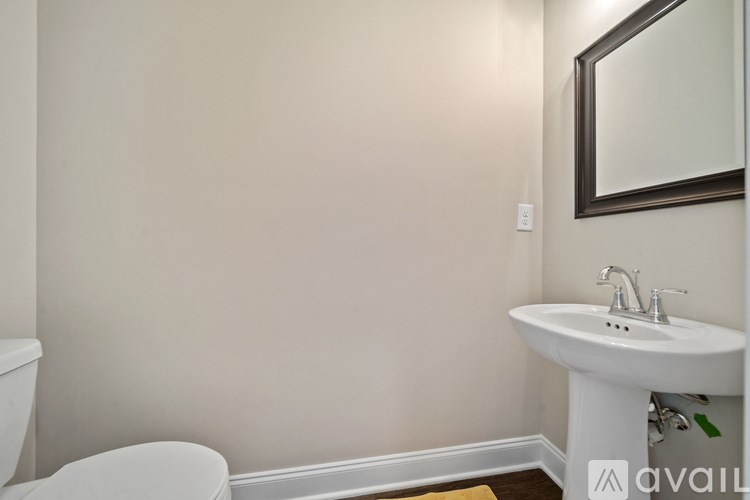 A bathroom with a white toilet and a white pedestal sink with a mirror above it.
