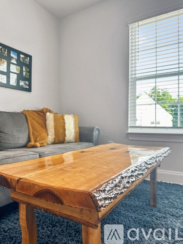 A wooden table with a grey couch and a blue carpet in a room.