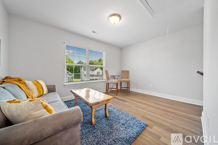 A living room with a grey couch, a wooden coffee table, and a window with a view of a fence and a house.
