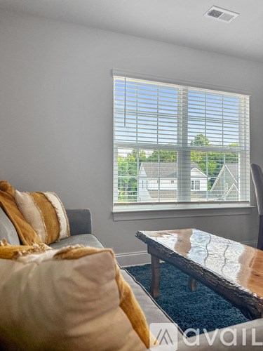 A living room with a couch, a table, and a window with blinds.
