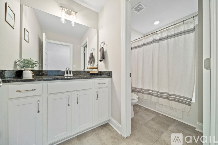 A bathroom with white cabinets and a black countertop.