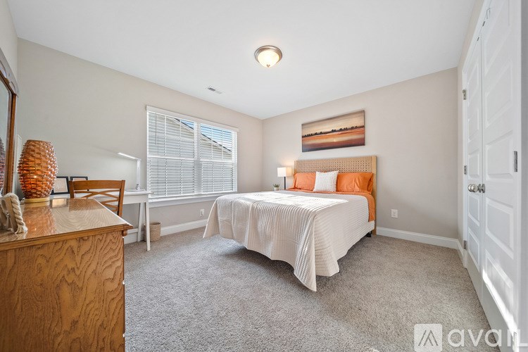 A bedroom with a bed, dresser, and window.