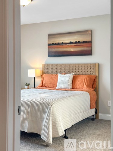 A bedroom with a bed, pillows, and a painting on the wall.