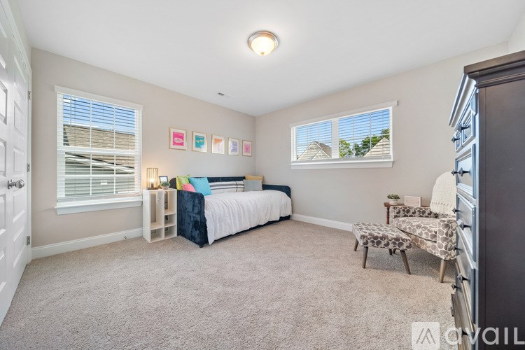 A bedroom with a bed, a chair, and pictures on the wall.