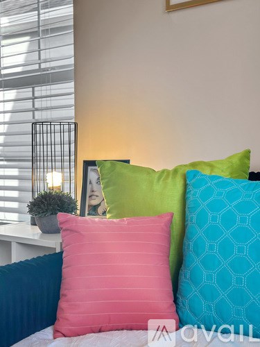 A bed with a white headboard and four pillows in different colors.