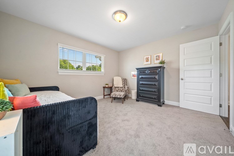 A bedroom with a bed, chair, and dresser.