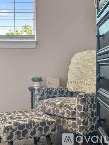 A chair with a patterned cushion sits in front of a window.